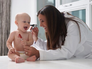 A baby is being checked for an ear infection by a pediatrician.