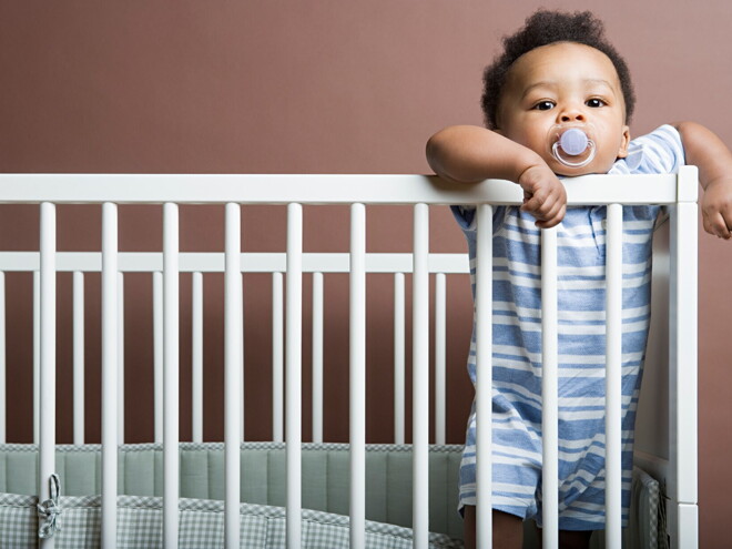 A Baby boy standing in cot