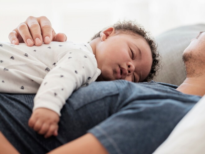 A child enjoying a baby sleep in his father’s chest