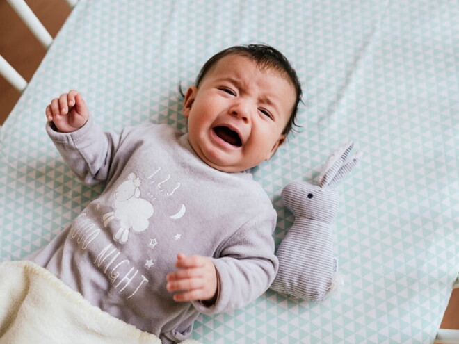 A baby crying inside their crib.