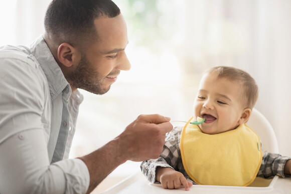 A father giving his baby his first food.