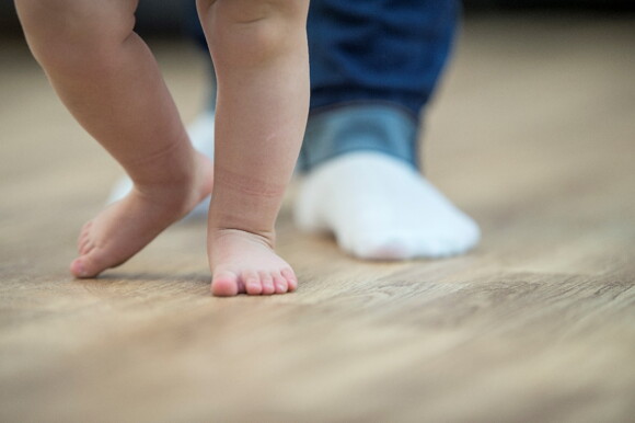 A baby’s feet practicing their first steps.