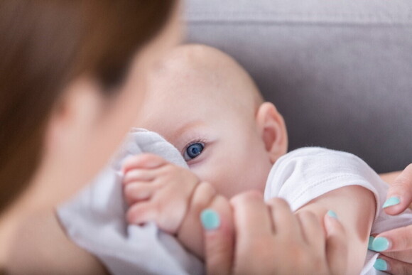 A baby looking at their mother while breastfeeding