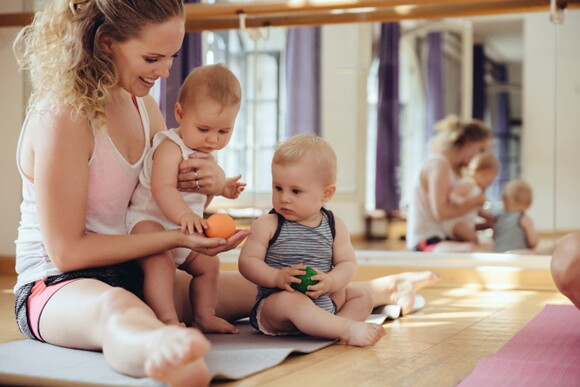 A woman exercising with her children on a yoga mat.