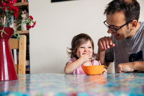 A dad sharing a family meal for toddlers with his daughter.
