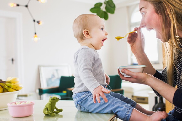 A mother feeding her baby with infant solid food.