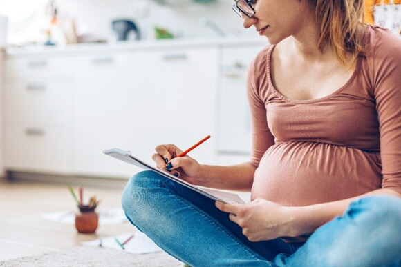 A pregnant woman taking notes about parenthood