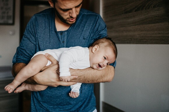 A father comforting his baby in a soothing position.